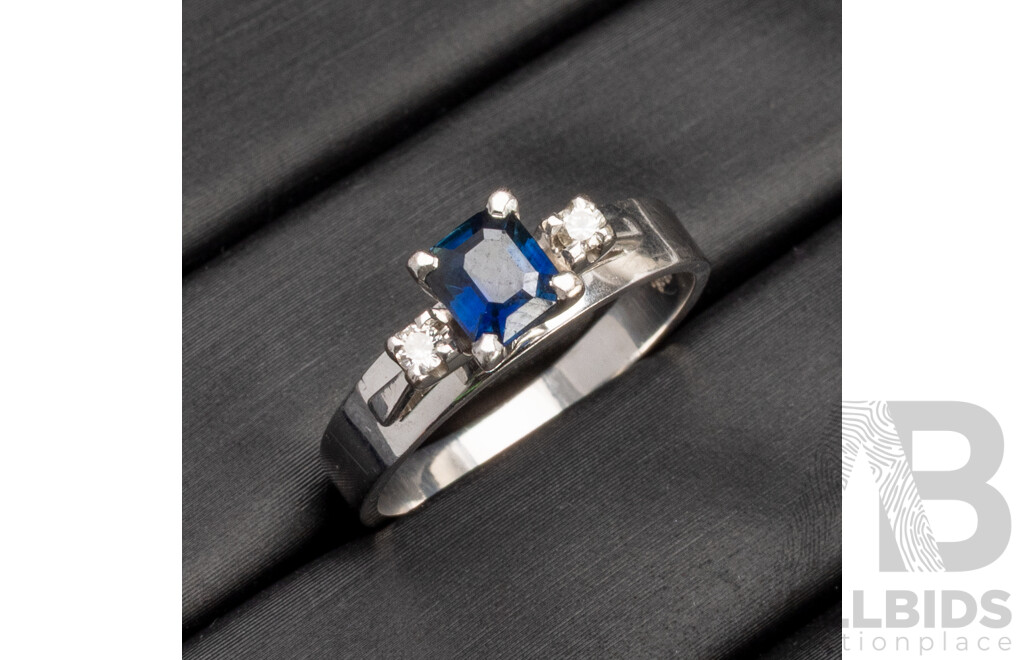 18 White Gold Ring with Emerald Cut Deep Blue Sapphire and 2x Shoulder Diamonds - Size M.5